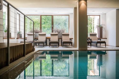 a room with a pool and chairs and windows at Naturhotel Rainer in Racines