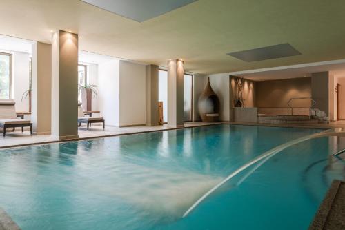 a large swimming pool with blue water in a building at Naturhotel Rainer in Racines