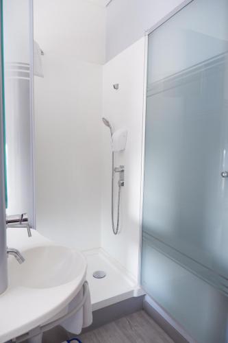 a white bathroom with a shower and a sink at MD 7 Hotel Cirebon in Cirebon