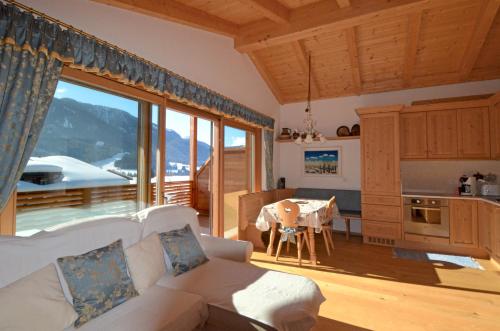 ein Wohnzimmer mit einem Sofa und eine Küche mit einem Tisch in der Unterkunft Aurturist Dobbiaco Roulette in Toblach