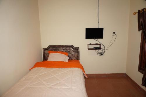 a small bedroom with a bed with an orange blanket at QQ Guesthouse in Kalasan