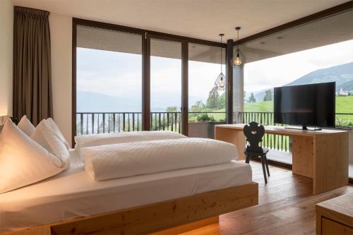 1 dormitorio con 1 cama y escritorio con TV en Hotel Fischer, en Bresanona