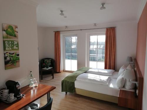 Schlafzimmer mit einem Bett, einem Schreibtisch und Fenstern in der Unterkunft Hotel Villa Passion in Malchow