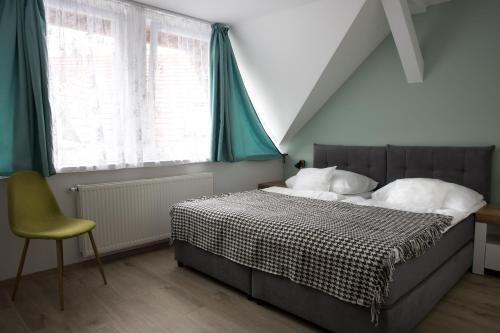 een slaapkamer met een bed, een stoel en een raam bij Tó-Part Panzió Kőszeg in Kőszeg