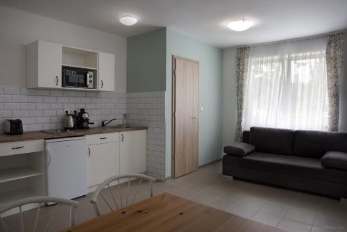 a kitchen and a living room with a couch and a table at Tó-Part Panzió Kőszeg in Kőszeg