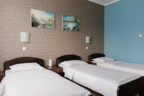 a room with three beds and paintings on the wall at Hotel Drinska lasta in Ljubovija