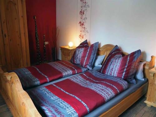 ein Bett mit roten und blauen Kissen darauf in der Unterkunft Ferienwohnung an der Waldmühle in Reulbach
