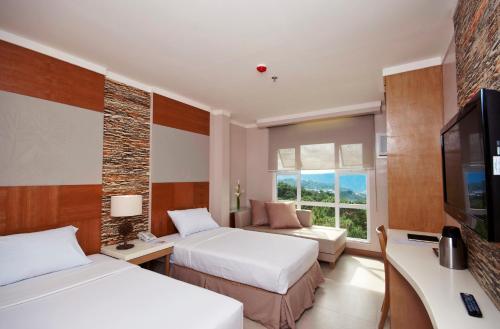 a hotel room with two beds and a flat screen tv at Chalet Baguio in Baguio