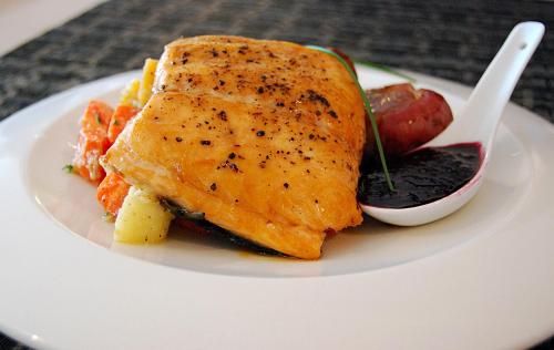 a white plate with a fish sandwich and sauce at Anchor Inn Hotel and Suites in Twillingate