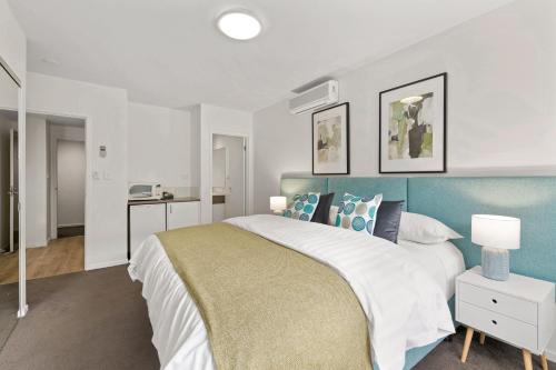 a bedroom with a large bed with a blue headboard at Burwood Serviced Apartments in Burwood