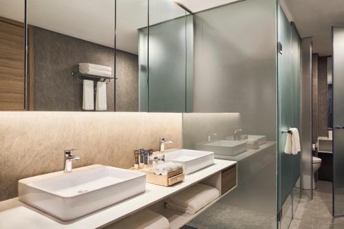 a bathroom with two sinks and a mirror at Novotel Hanoi Thai Ha in Hanoi