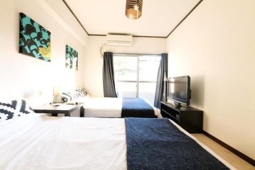 1 dormitorio con 2 camas, TV y ventana en H2O Stay Kikukawa Woody Sunheim #201 en Tokio