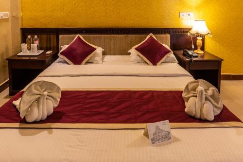 een hotelkamer met een groot bed met twee tafels bij KSTDC Hotel Mayura Chalukya, Badami in Badami