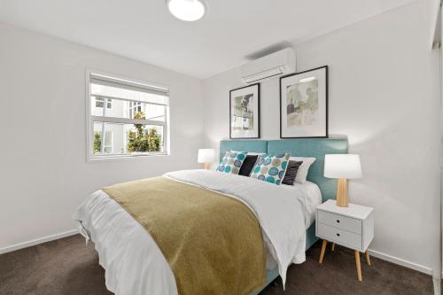 a white bedroom with a bed and two windows at Burwood Serviced Apartments in Burwood