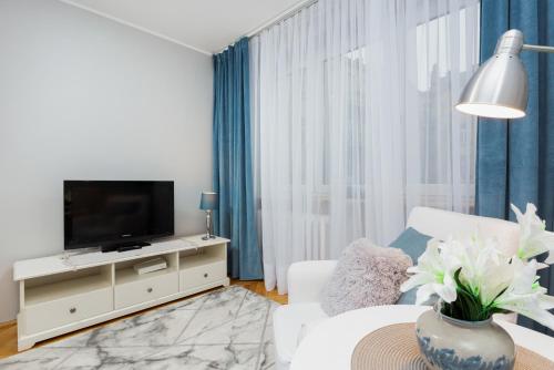 sala de estar con TV y sofá blanco en Apartment Warsaw Kredytowa by Renters en Varsovia