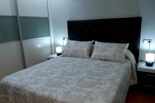 a bedroom with a large bed with two lamps on it at DISFRUTE DE SUS VACACIONES CON WIFI EN EL PUERTO DE CARIÑo in Cariño
