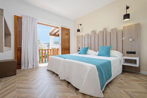 una camera con un grande letto e un balcone di azuLine Apartamentos Can Sanso a Santa Eularia des Riu