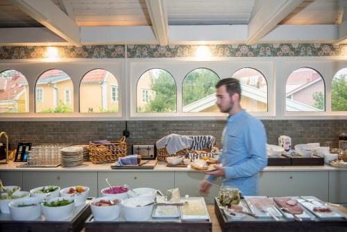 Ein Mann steht in einer Küche und bereitet Essen vor. in der Unterkunft Slottshotellet Annex in Kalmar