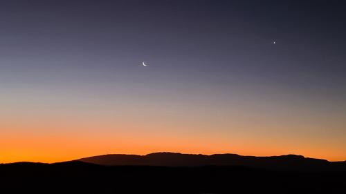 an orange sunset with the silhouettes of mountains at Rooiberg Wild Private Game Reserve in Ladismith