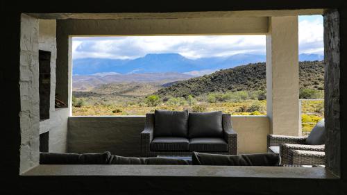 a living room with a couch and a large window at Rooiberg Wild Private Game Reserve in Ladismith