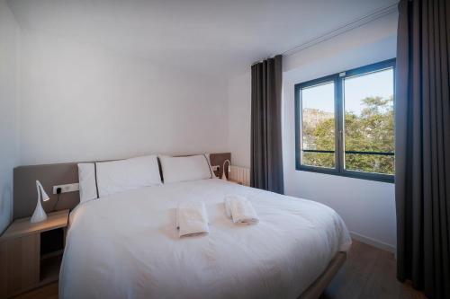 1 dormitorio con 1 cama blanca grande y 2 toallas en NC Apartments Rambla 32, en Figueres