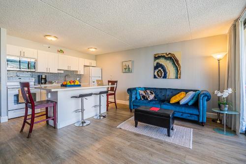 a living room with a blue couch and a kitchen at Pool & Jacuzzis, Free Parking, WiFi, AC, Comfy Beds, BBQ, and Great View in Honolulu