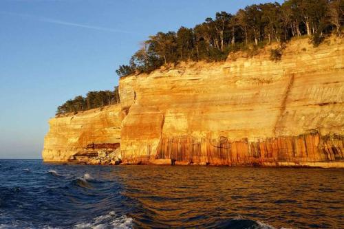 a cliff with trees on top of it next to the water at Comfort Suites in Marquette