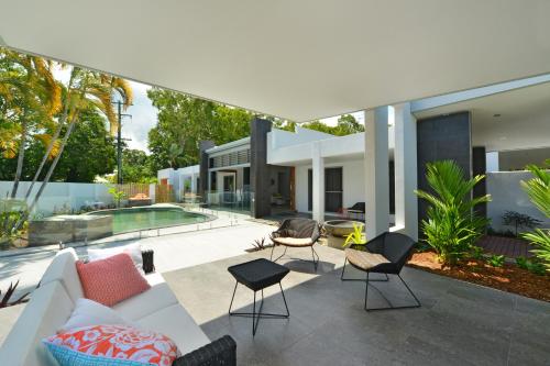 an outdoor patio with a white couch and chairs at #2 Andrews – Port Douglas in Port Douglas