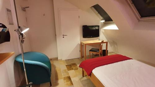 a small room with a bed and a chair at Domaine Leidinger in Saarbrücken