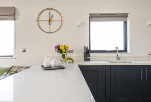 a kitchen with black cabinets and a large clock on the wall at Bramble in Ansty