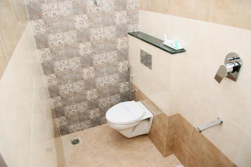 a bathroom with a toilet and a tiled wall at Apollo Court (Apollo hospital,Sankara natralya, US consulate in Chennai