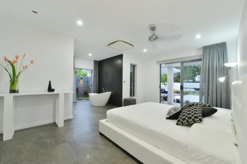 a white bedroom with a white bed and a bath tub at #2 Andrews – Port Douglas in Port Douglas