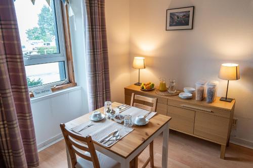 a dining room with a table and chairs and a window at Broadford House Skye in Broadford