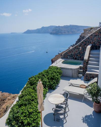a patio with a table and chairs and the ocean at Pezoules of Oia in Oia