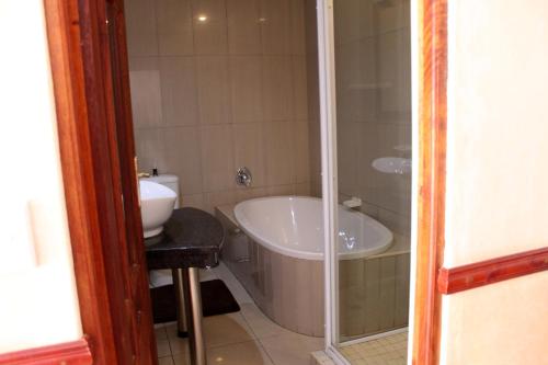 a bathroom with a tub and a toilet and a sink at Prinshof Manor Guesthouse in Pretoria