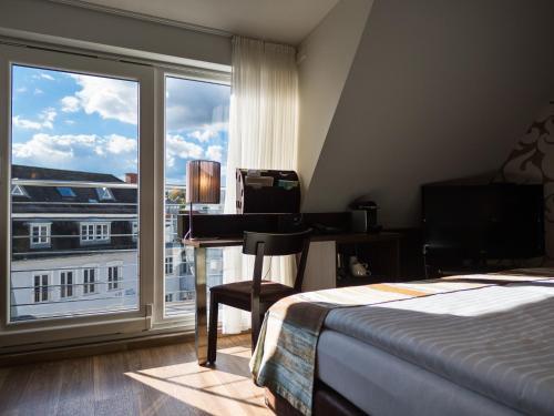 a bedroom with a bed and a desk and a window at Domaine Leidinger in Saarbrücken