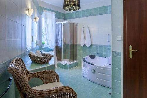 y baño con silla de mimbre y bañera. en Hotel Mikulski en Gliwice