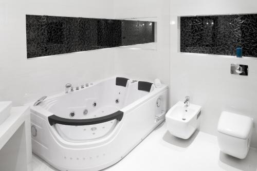a white bath tub sitting next to a white toilet at Hotel Mikulski in Gliwice