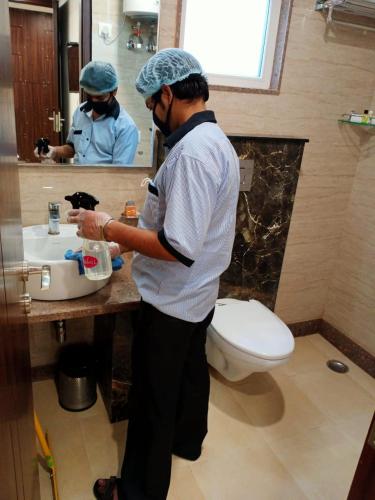 a man standing in a bathroom with a sink at Lemon Green Inn in New Delhi