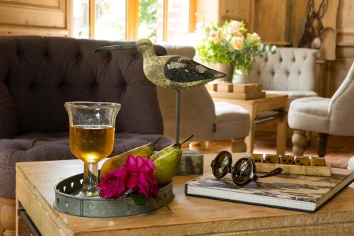 a coffee table with a drink and a bird statue on it at Auberge de la Source - Hôtel de Charme, Collection Saint-Siméon in Barneville-la-Bertran