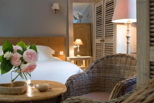 a bedroom with a bed and a table with a vase of flowers at Auberge de la Source - Hôtel de Charme, Collection Saint-Siméon in Barneville-la-Bertran