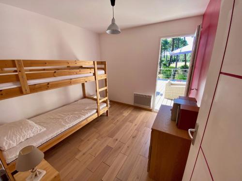 a bedroom with bunk beds and a desk and a window at Villa les Mimosas with pool and fantastic views in Lacanau
