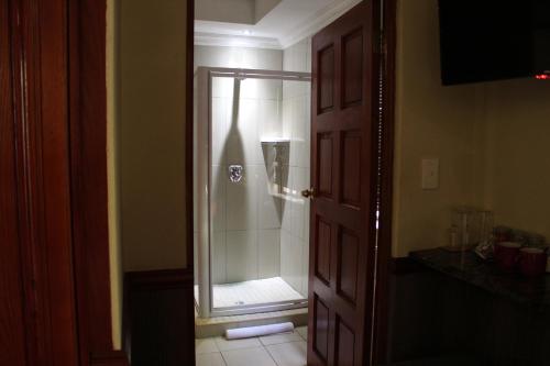 a bathroom with a shower with a glass door at Prinshof Manor Guesthouse in Pretoria