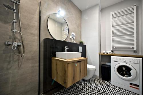 a bathroom with a sink and a washing machine at Komputerowa Street P&O Apartments C7 in Warsaw