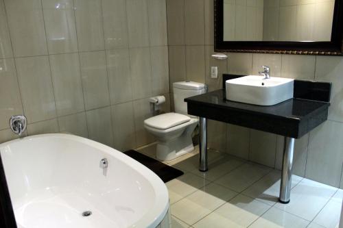 a bathroom with a tub and a sink and a toilet at Prinshof Manor Guesthouse in Pretoria
