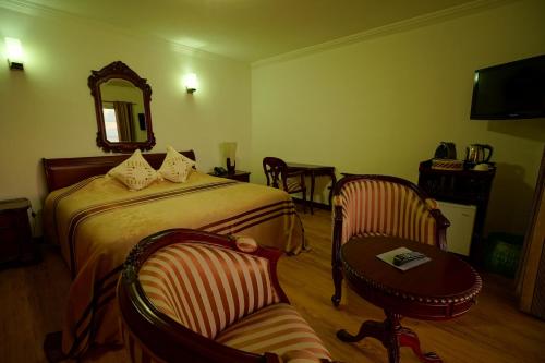 a bedroom with a bed and a table and a chair at Treasure Cove Hotel & Restaurant in Bel Ombre