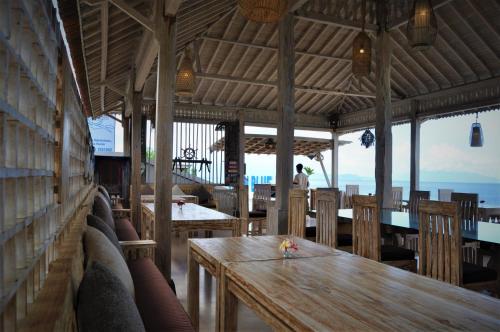 a restaurant with a wooden table and chairs at Ocean Terrace Suite And Spa Luxury in Nusa Penida