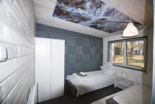 ein kleines Schlafzimmer mit einem Bett und einem Fenster in der Unterkunft Kompleks Wypoczynkowy ANApausis in Gryżyna