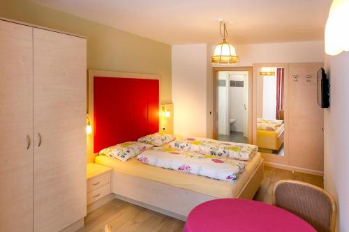 sypialnia z łóżkiem z czerwoną głowicą w obiekcie Apartments Diamant w mieście Ortisei
