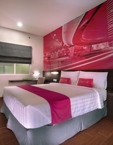 a bedroom with a large bed with a red wall at favehotel Graha Agung Surabaya in Surabaya
